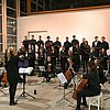 Auf dem Bild ist der Chor und das Orchester der TH Rosenheim bei einem Konzert im Foyer der Hochschule zu sehen.